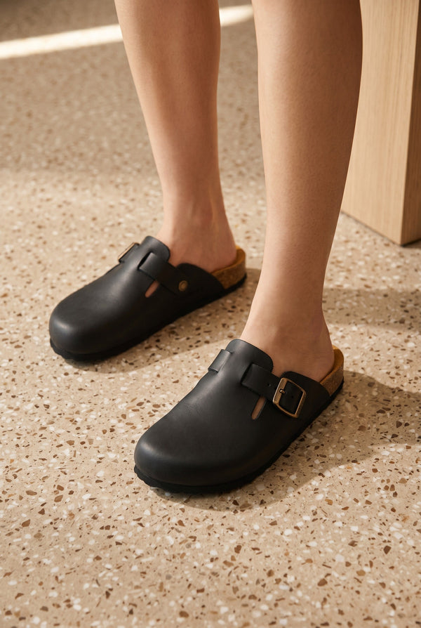 Sabot SAHELY noir en cuir mat André avec boucle réglable et semelle intérieure en liège pour un confort optimal.