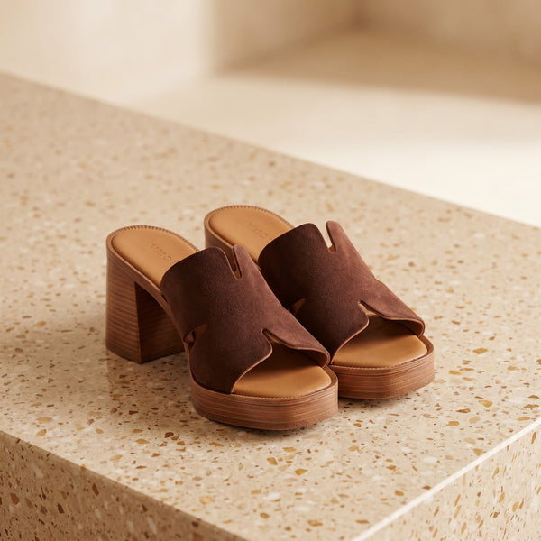 André mules en croûte de cuir marron avec talon en bois et découpes originales.