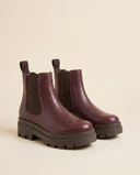 Boots ALCALINA bordeaux debout sur fond beige
