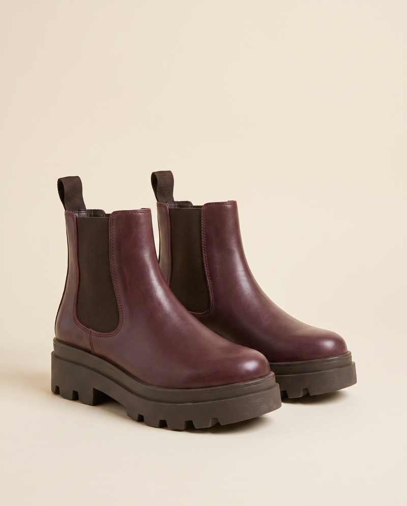 Boots ALCALINA bordeaux debout sur fond beige