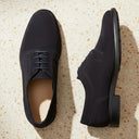 André derby en cuir suède bleu marine, lacets assortis, semelle fine et légère, style minimaliste et moderne.