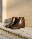 Paire de boots SAMIRA marron posée sur une marche en pierre — A by André