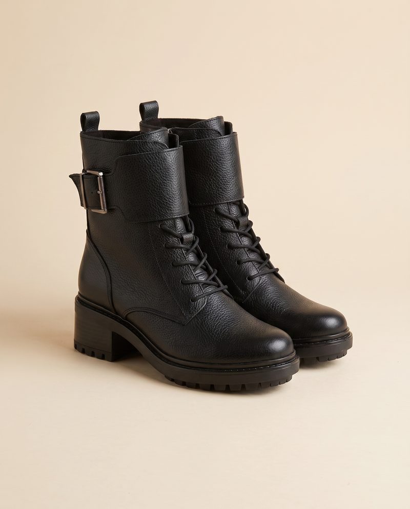 Boots ENLACE noires debout sur fond beige