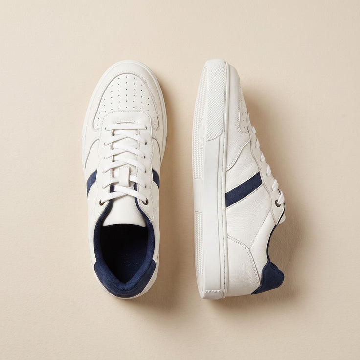 André baskets en cuir blanc avec rayures et lacets bleu marine, style décontracté et chic.