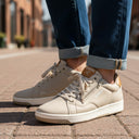 André Gobat beige suede sneakers with camel heel and tongue details, side zip, and white soles.