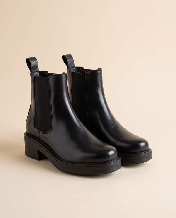 Boots HEDIA noires debout sur fond beige