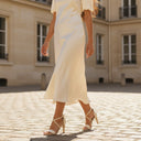 André ILYANA beige leather heeled sandals with criss-cross straps and buckle closure.