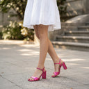 Sandales à talons André Impressionnante Rose métallisé avec bride cheville, portées avec une robe blanche en broderie