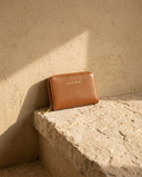 Petit portefeuille MINI BUCI cognac Maison André sur une marche en pierre