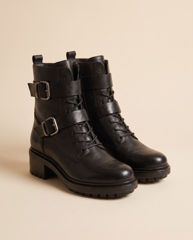 Boots NIMA noires debout sur fond beige