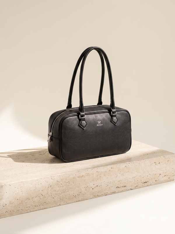 Sac bowling Noélie noir posé sur une marche en pierre de travertin, fond ivoire
