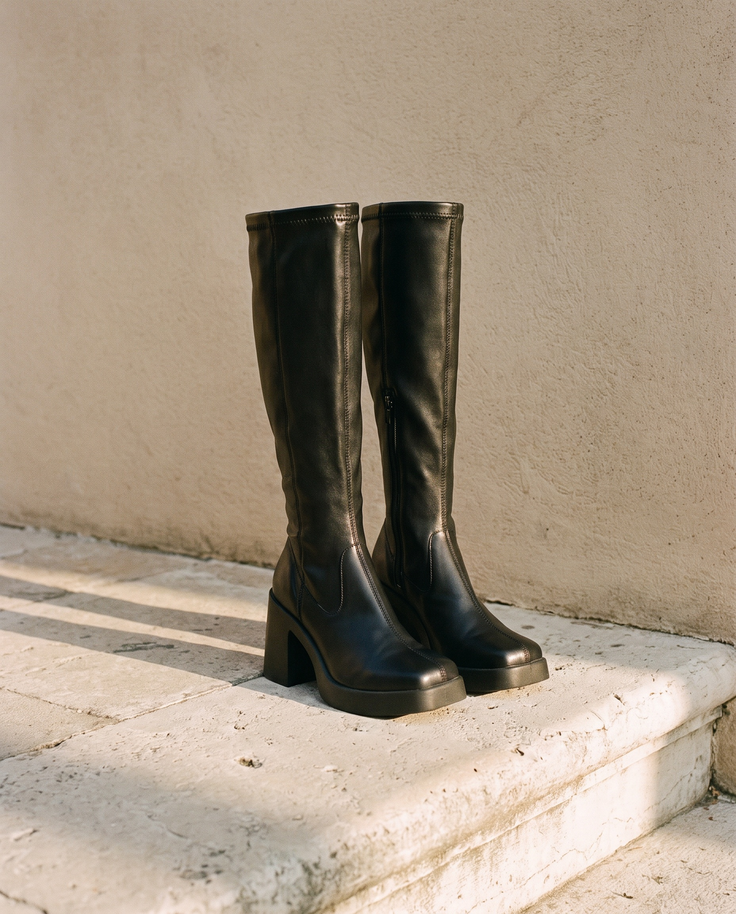 Paire de bottes RATA noires posée sur une marche en pierre — André