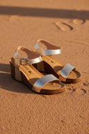 Sandales compensées André en cuir doré avec bride à boucle et talon de 6 cm. Parfaites pour l'été.