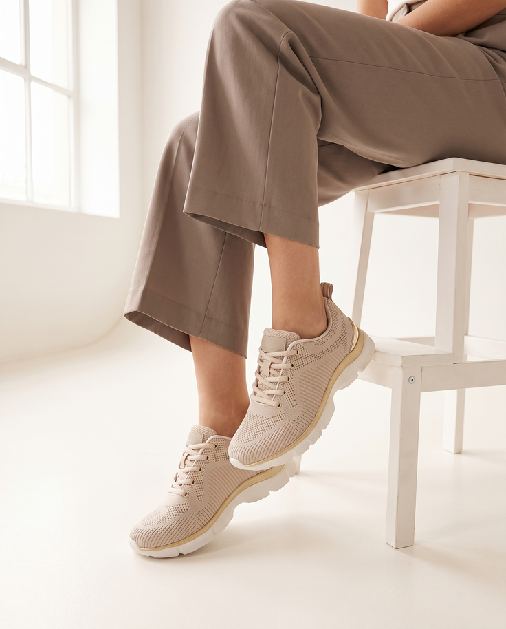 Basket SERAPIS beige portée, gros plan, femme assise jambes croisées sur un tabouret blanc en studio
