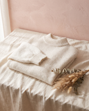 Pull paillettes Solveig écru, posé sur un lin crème, mur rose poudré