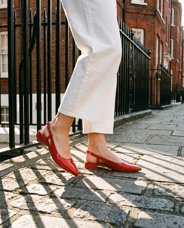 Slingback THALASSA rouge portée, gros plan, sur les pavés d'une rue londonienne