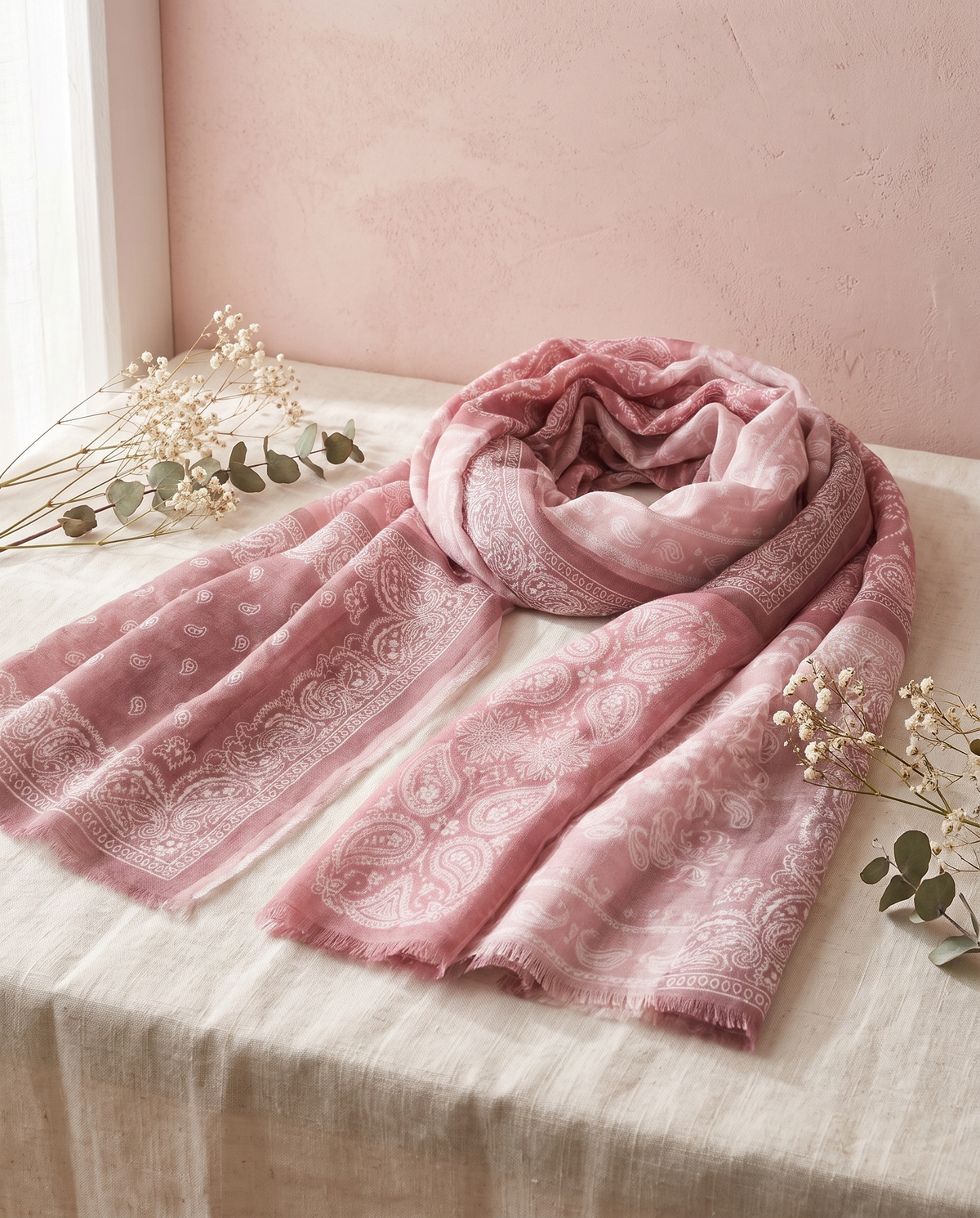 Écharpe bandana Zoelle rose, posée sur un lin crème, mur rose poudré
